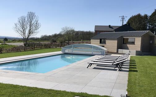 foto van een mooi rechthoekig buitenzwembad met 4 ligzetels, voor een chalet