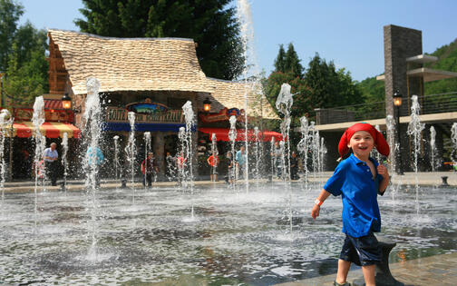 kleuter met rode plopmuts en blauw t-shirt in waterattractie de dansende fonteinen