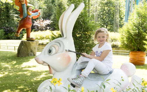 meisje op attractie in Plopsa Coo: een hobbelend konijn