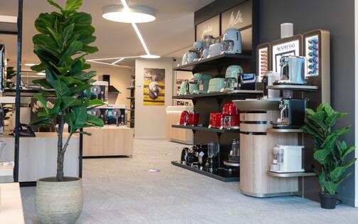 stand met koffieapparaten, koffiekannen en toebehoren + nespressomachine waar klanten koffie kunnen nemen in winkel