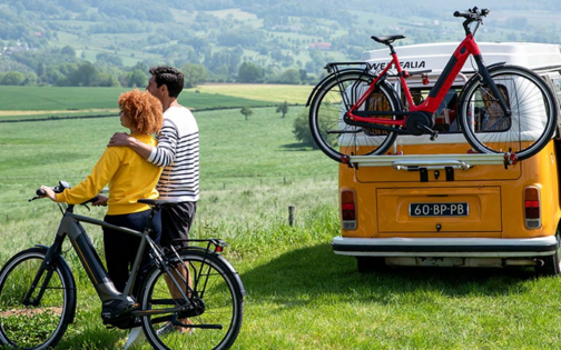 koppel staat naast fiets en geniet van het uitzicht, naast een vintage busje volkswagen