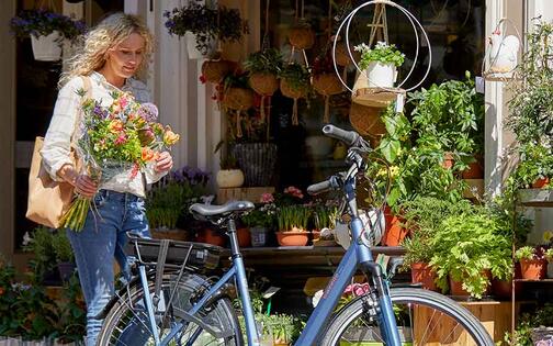 vrouw met fiets aan een bloemenwinkel