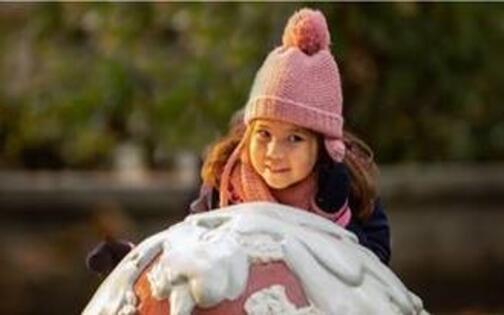meisje met roze muts aan grote sneeuwbal