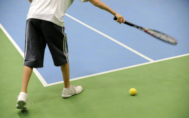 jongen tennist op indoorterrein