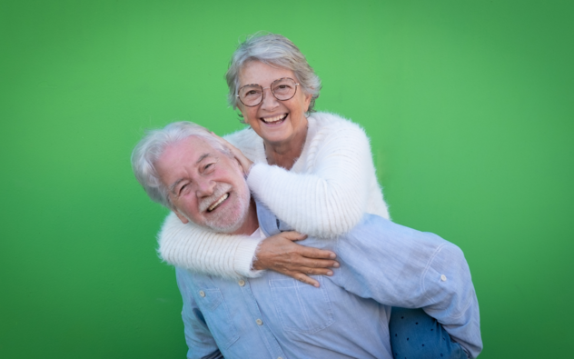 2 gelukkige ouderen, vrouw zit op rug van de man