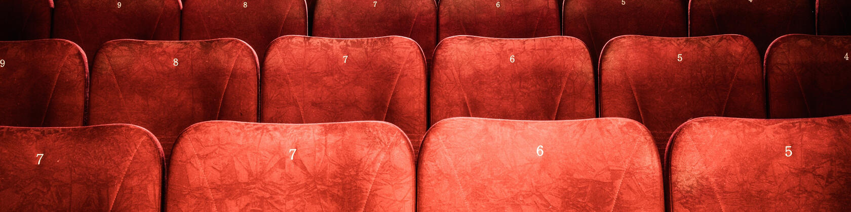 foto van een lege filmzaal met rode stoelen