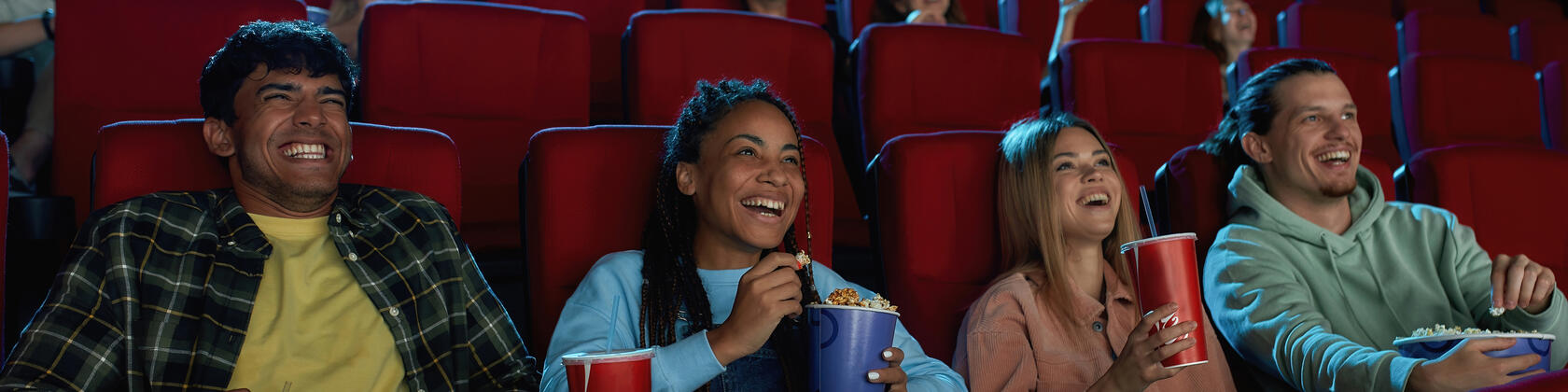 3 mensen in de cinema met popcorn, ze lachen